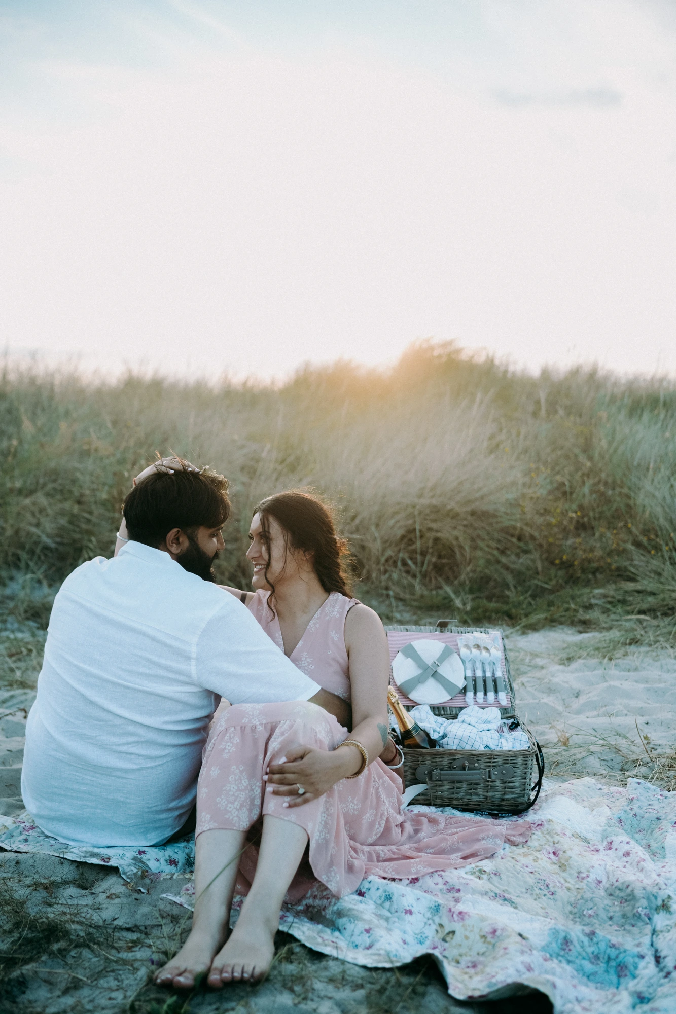 Couple sharing a picnic on the beach at golden hour