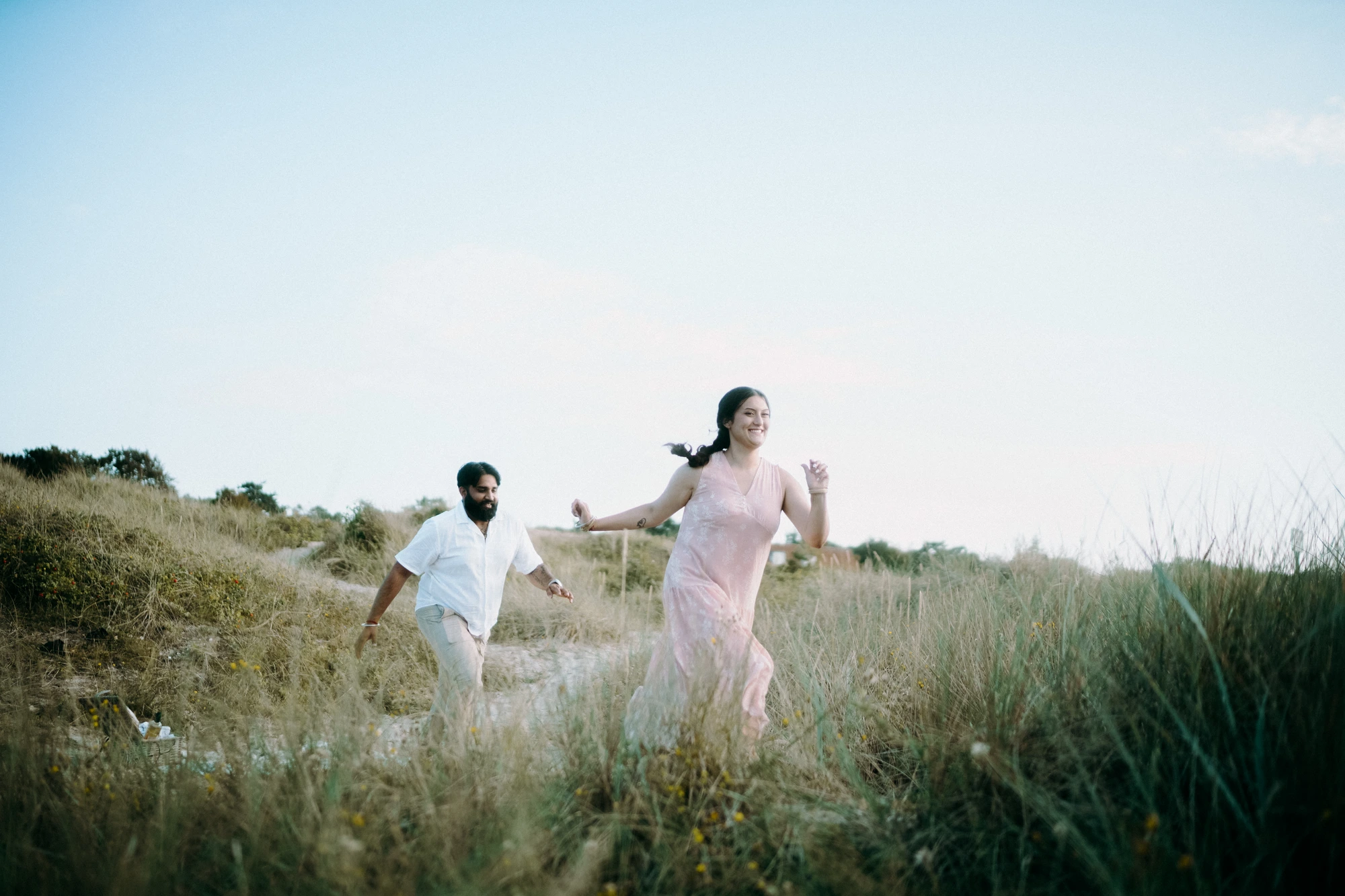 Couple laughing and running through golden dunes