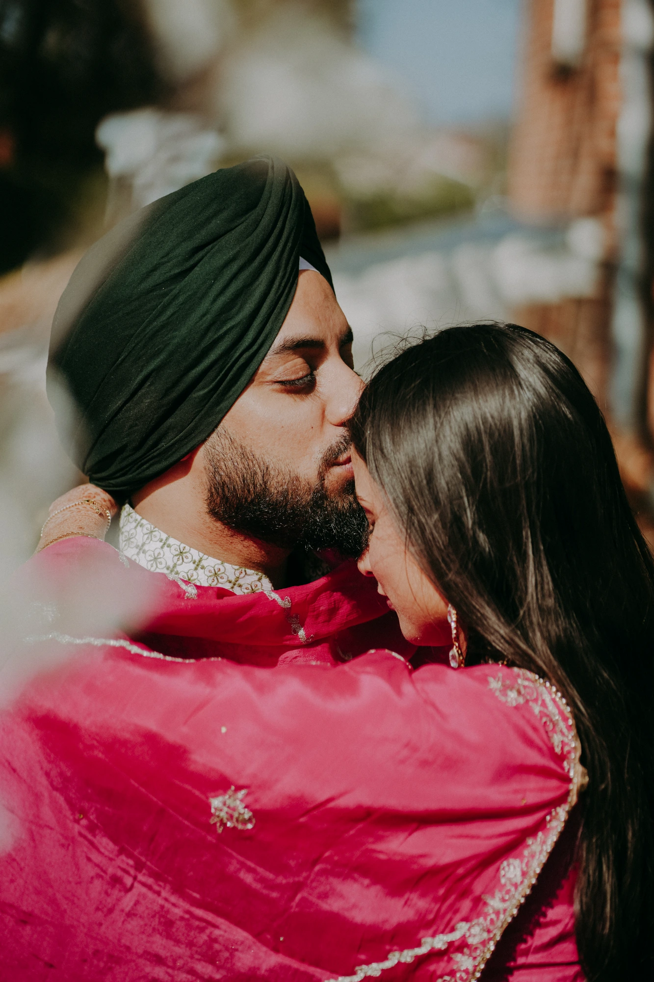 Couple sharing a kiss beneath a red veil